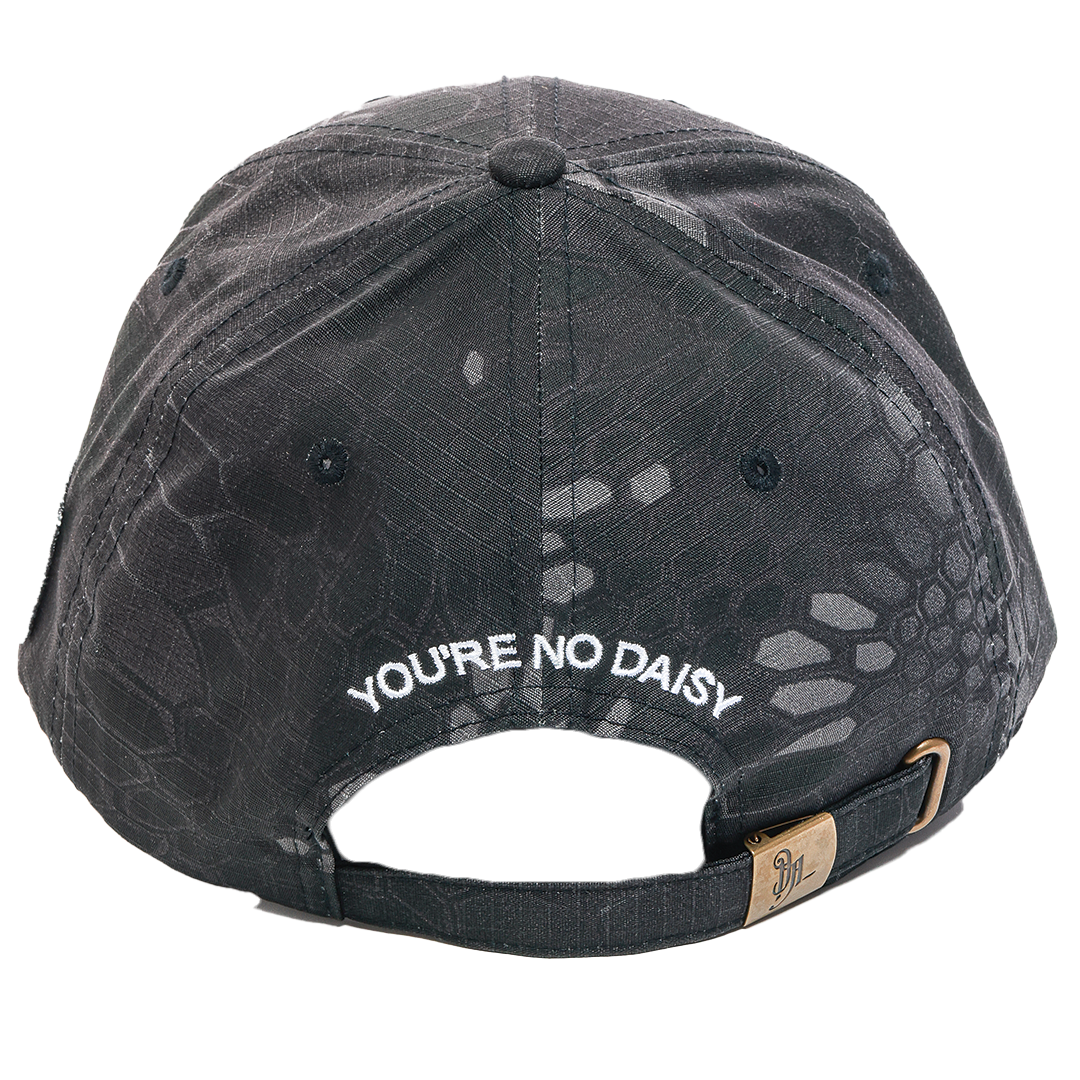 Back view of a black textured baseball cap with white embroidered text reading 'YOU'RE NO DAISY' and a small gold-toned brand tag on the adjustable strap.